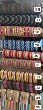 Rolls of colorful zigzag knit fabric in various patterns and stripes for evening wear and garments, 150cm wide.