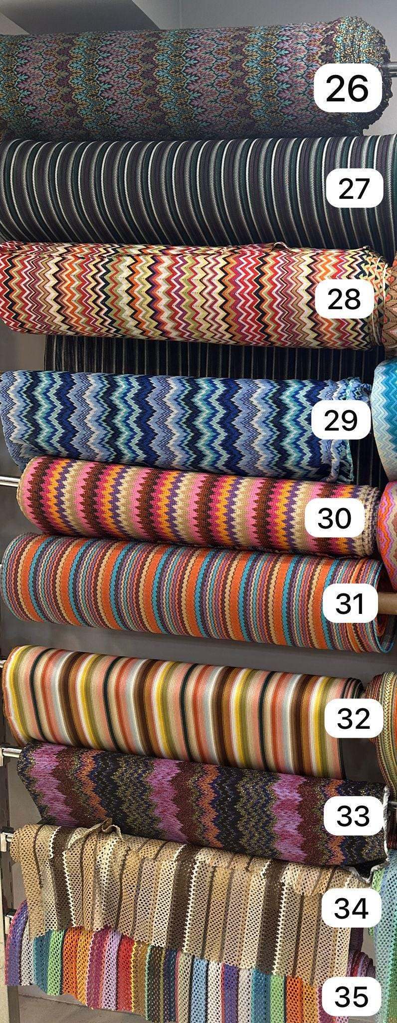 Rolls of colorful zigzag knit fabric in various patterns and stripes for evening wear and garments, 150cm wide.