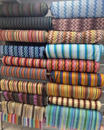 Colorful rolls of zigzag knit fabric in various patterns and stripes for dressmaking and apparel use