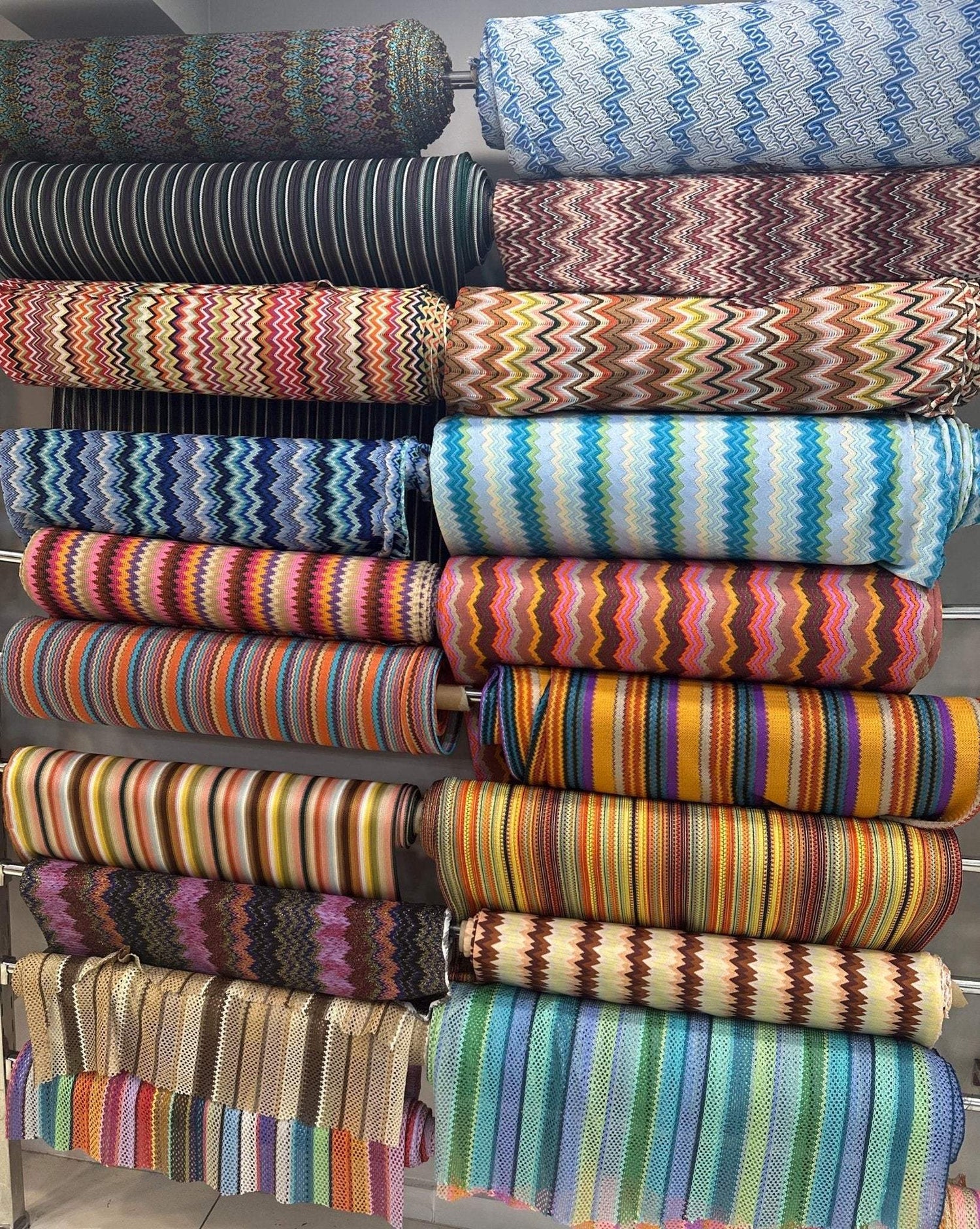 Colorful rolls of zigzag knit fabric in various patterns and stripes for dressmaking and apparel use