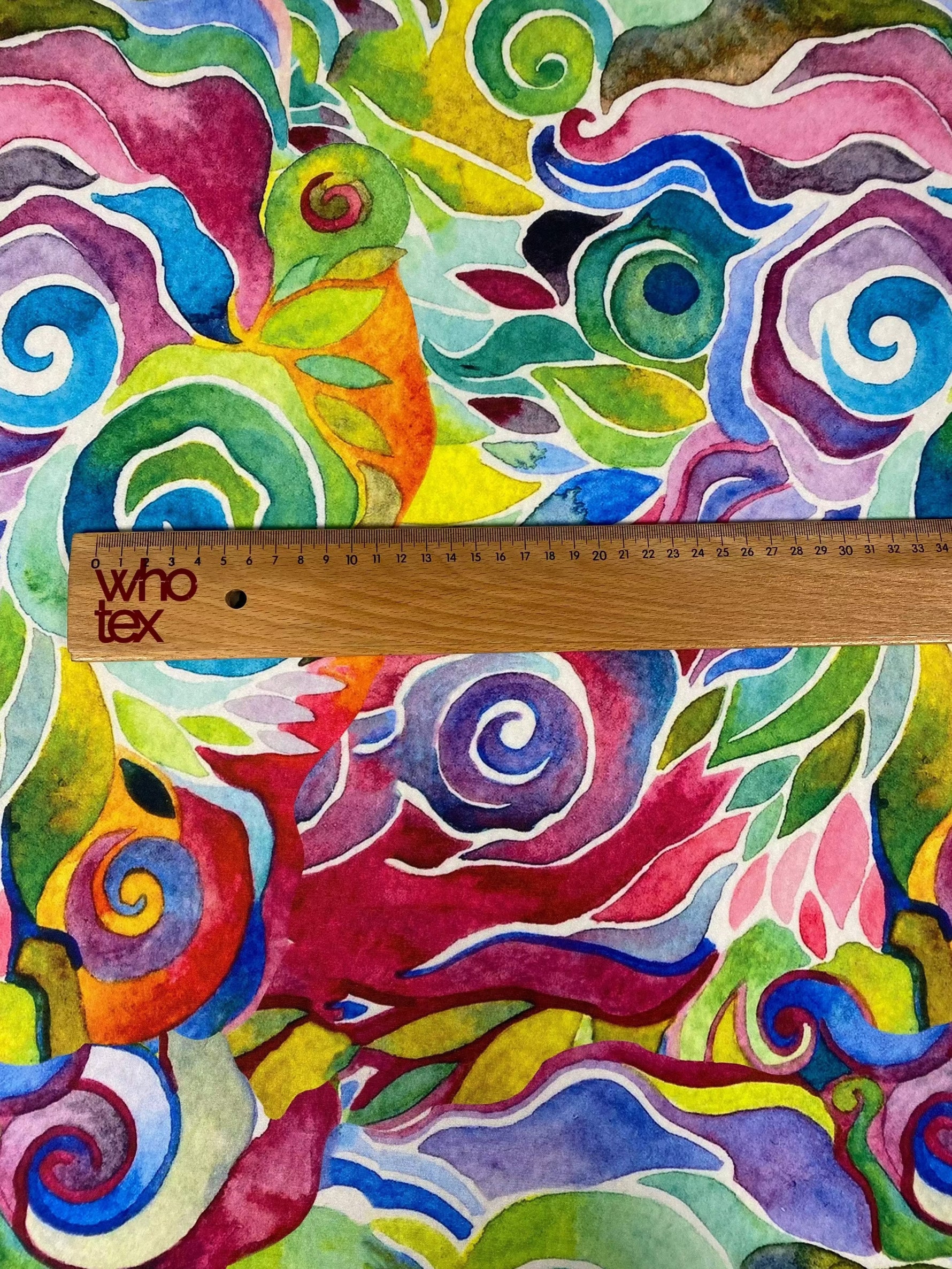 Colorful abstract floral swirl fabric with vibrant multicolored pattern and ruler for scale