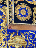 Royal blue baroque fabric with intricate gold patterns and cherub motifs, shown with ruler for scale