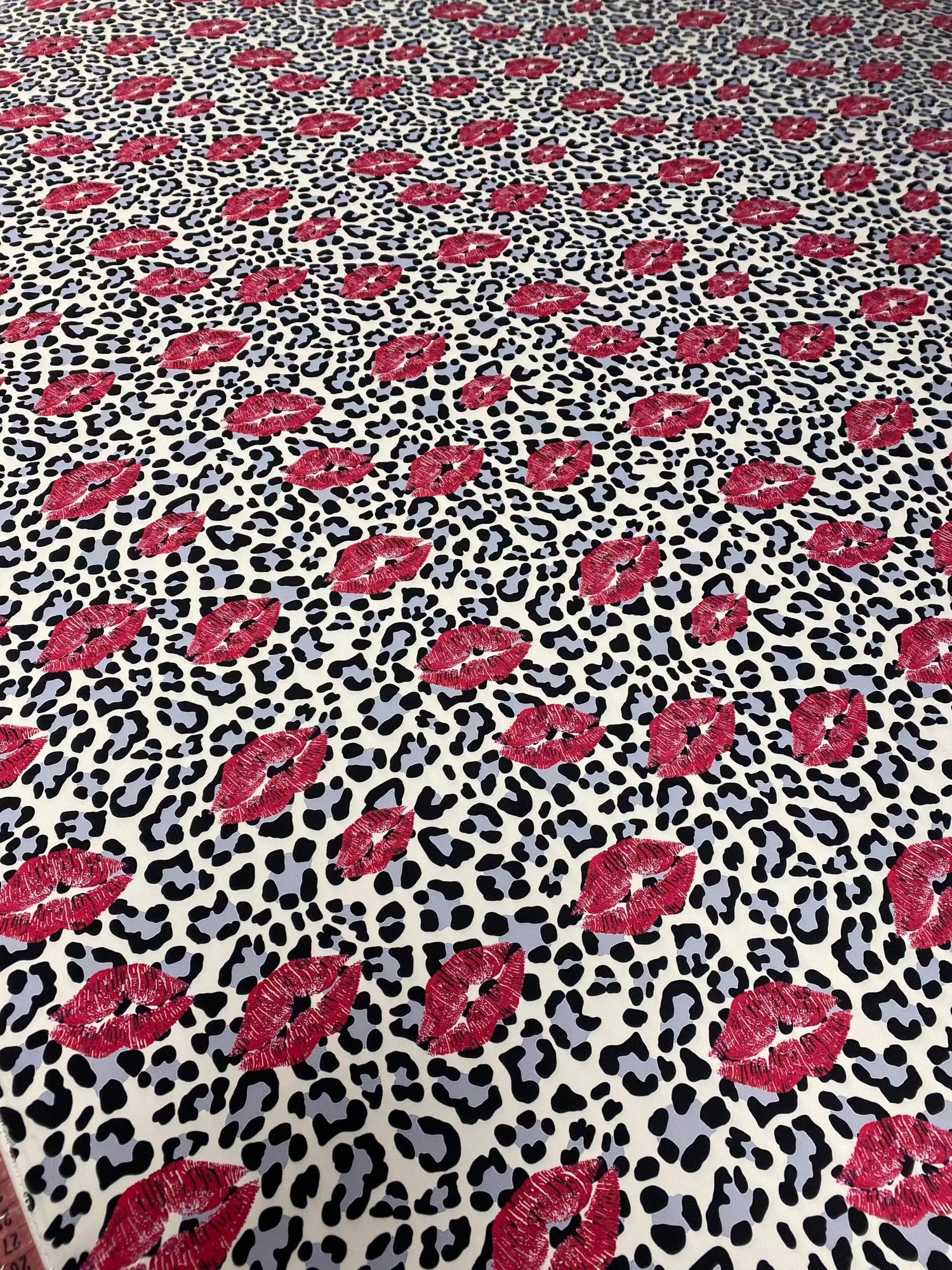 Leopard print fabric with bold black spots and pink lip pattern for upholstery and home decor projects