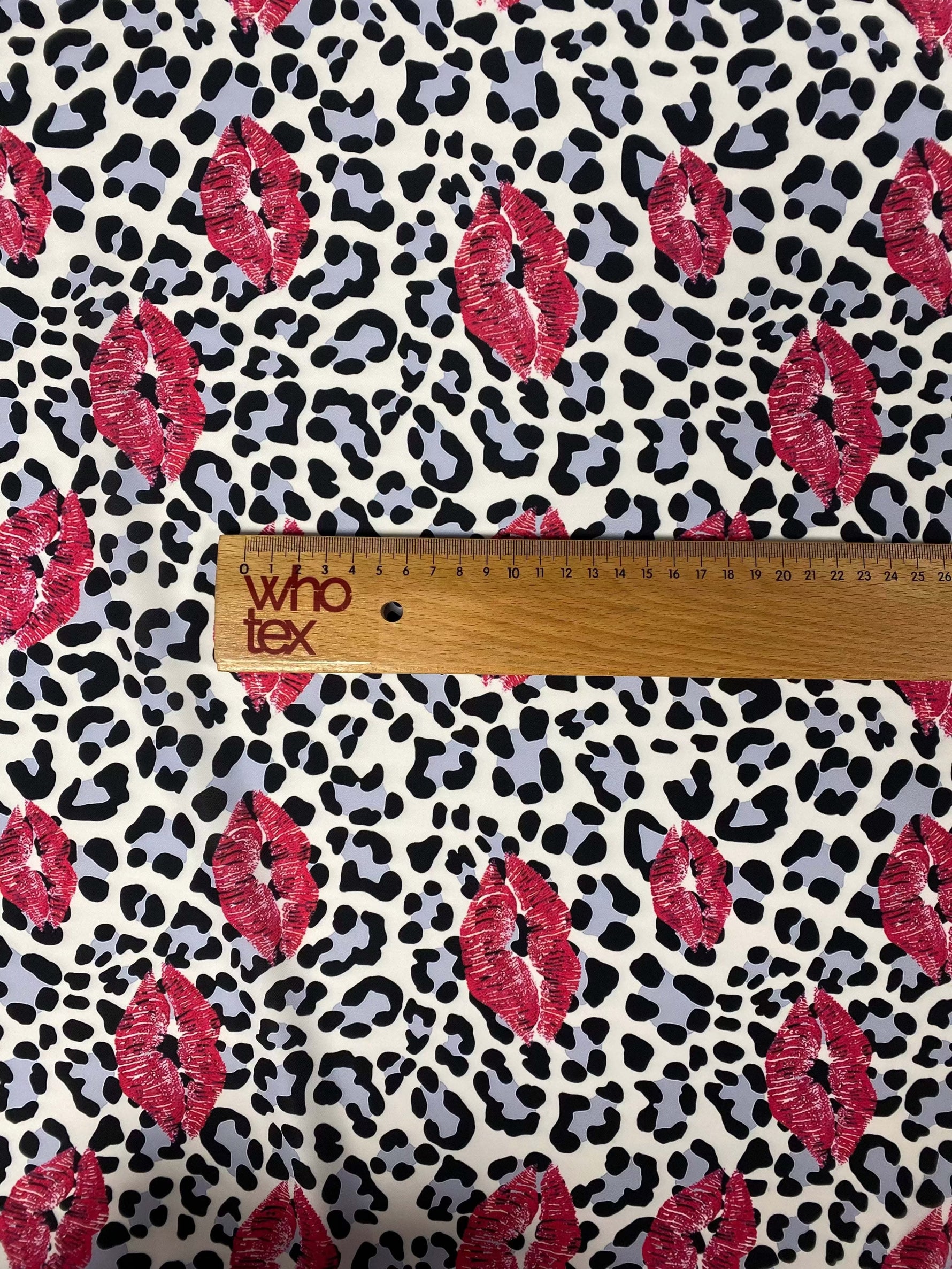 Leopard print fabric with pink lip pattern and ruler for scale on white background