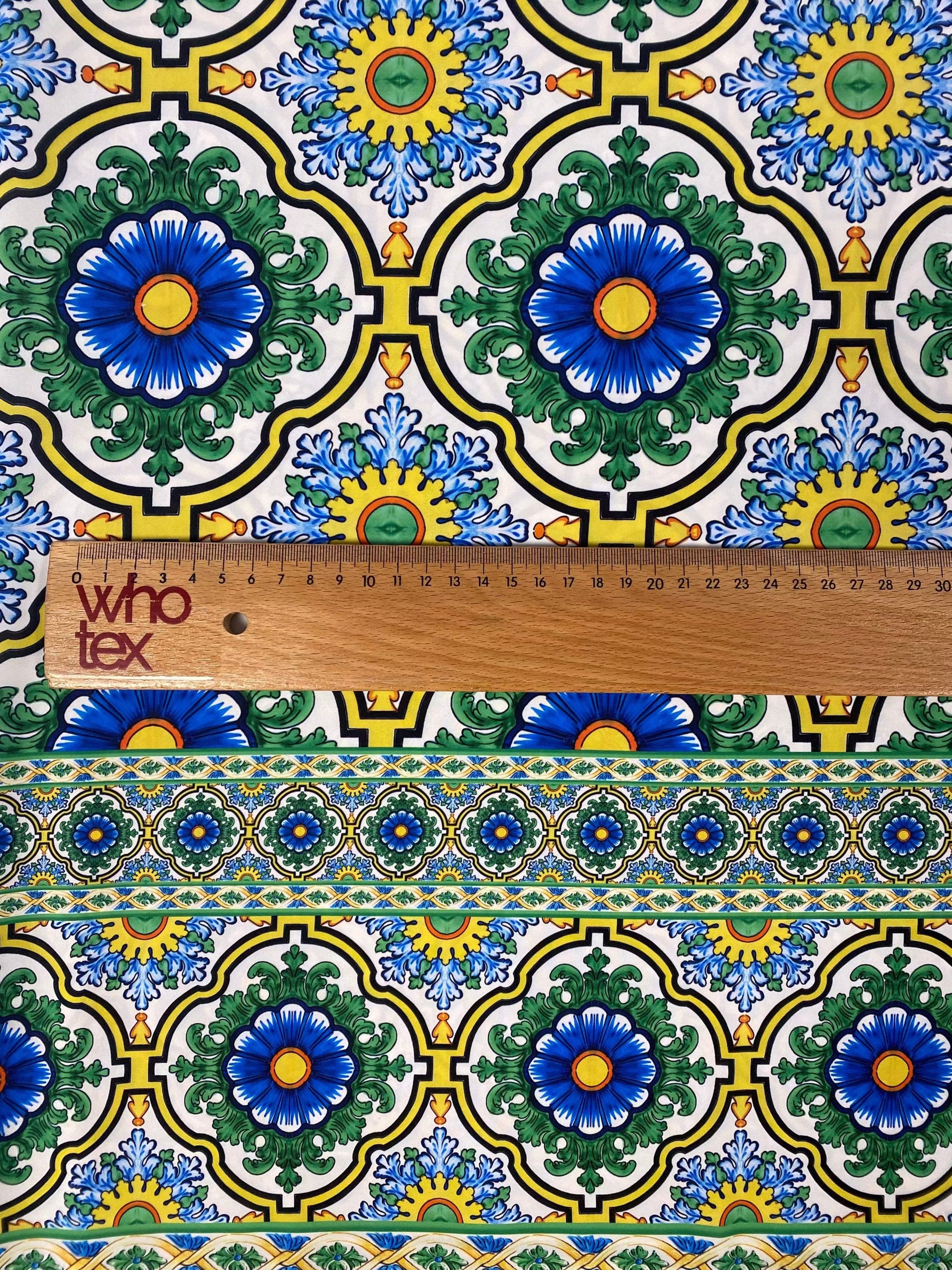 Sicilian pattern green fabric with intricate blue and yellow floral design and measuring ruler for scale