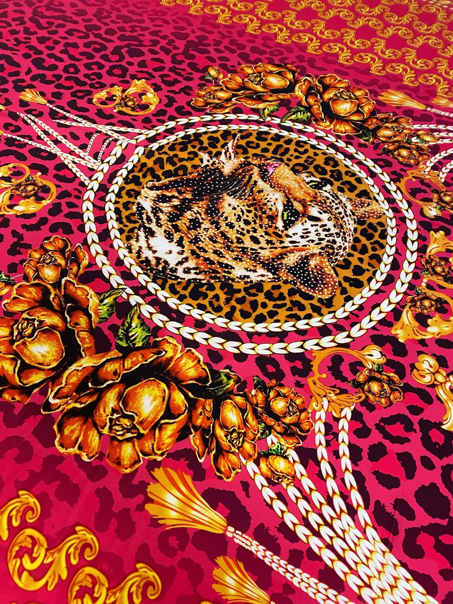 Fuchsia leopard print fabric with baroque gold floral and rope patterns featuring a leopard head centerpiece