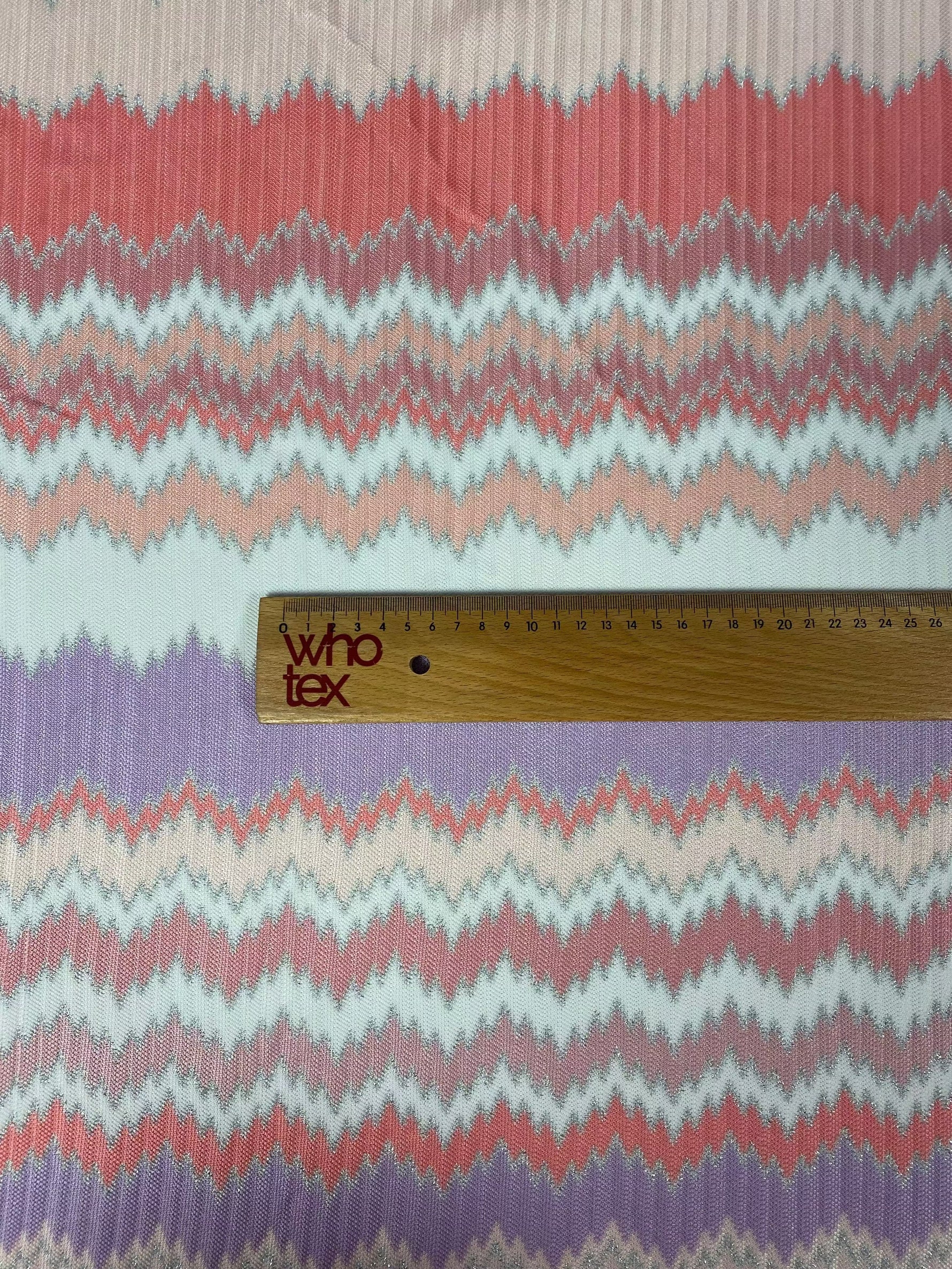 Purple and coral zigzag woven fabric with metallic accents and ruler for scale