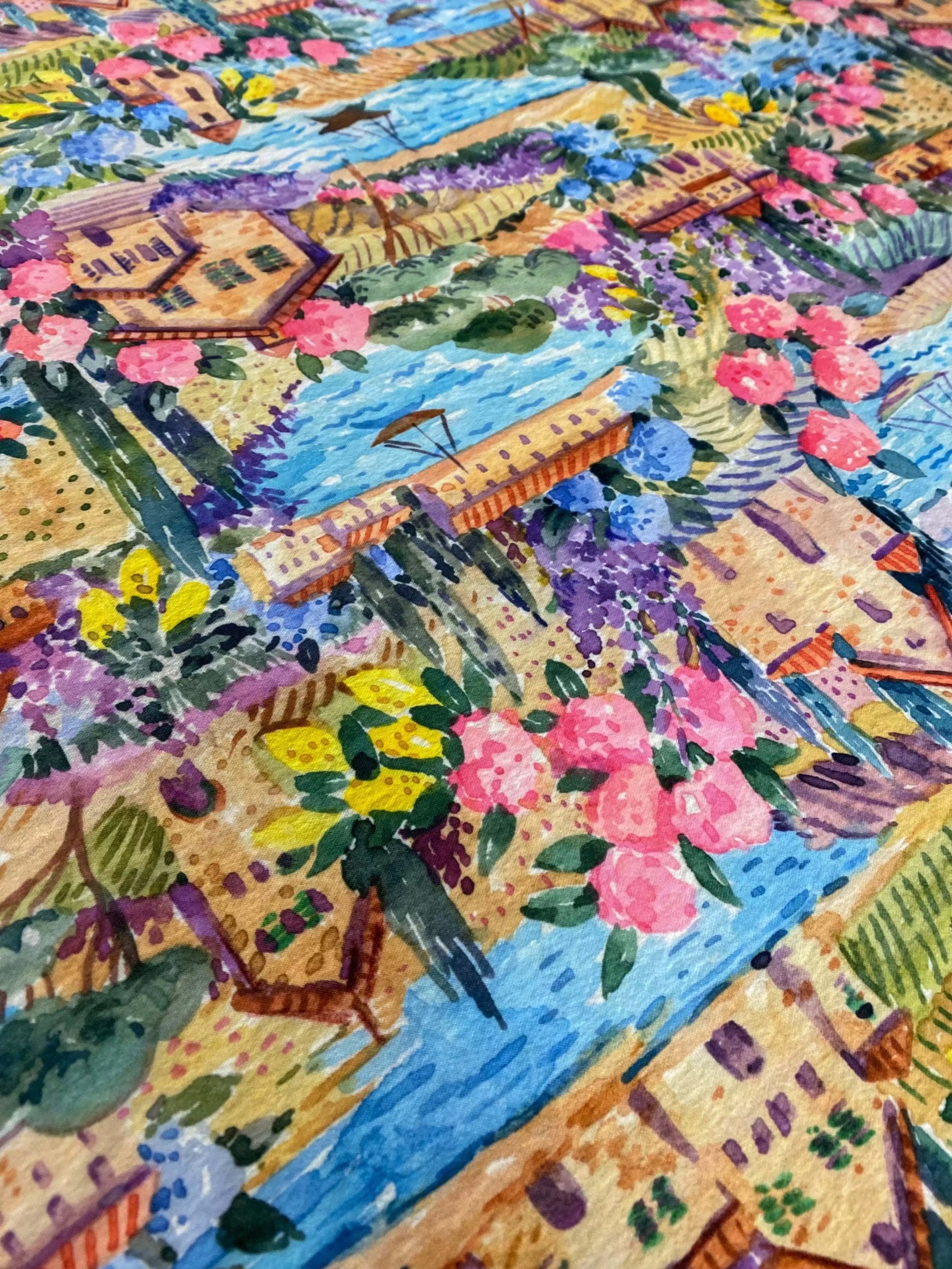 Close-up of watercolor coastal village print fabric with colorful houses, flowers, and waterways in soft tones