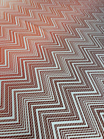 Close-up of red and white chevron patterned fabric with a textured surface and 150cm width, ideal for sewing and crafting projects