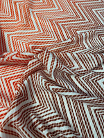 Close-up of red and white chevron patterned fabric with textured weave and 150cm width
