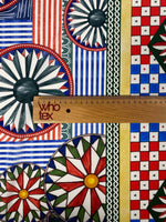 Sicilian Caretto Pattern Fabric with vibrant geometric and floral designs in red, blue, green, and yellow colors, measured with a wooden ruler.