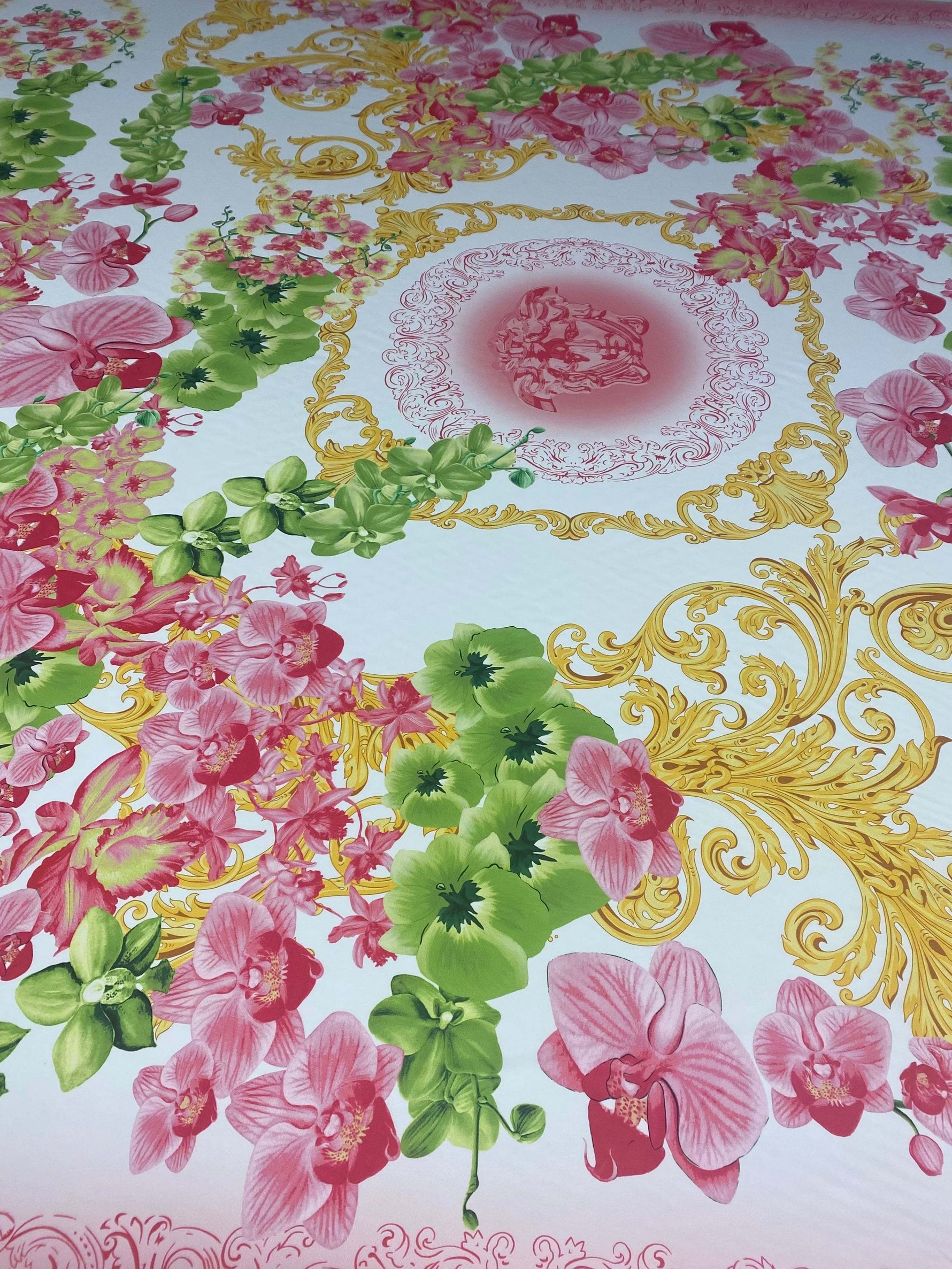 Orchid swirl print fabric with pink orchids, green leaves, and golden decorative swirls on a white background