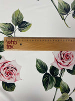 Pink rose floral fabric on white background with green leaves and ruler for scale