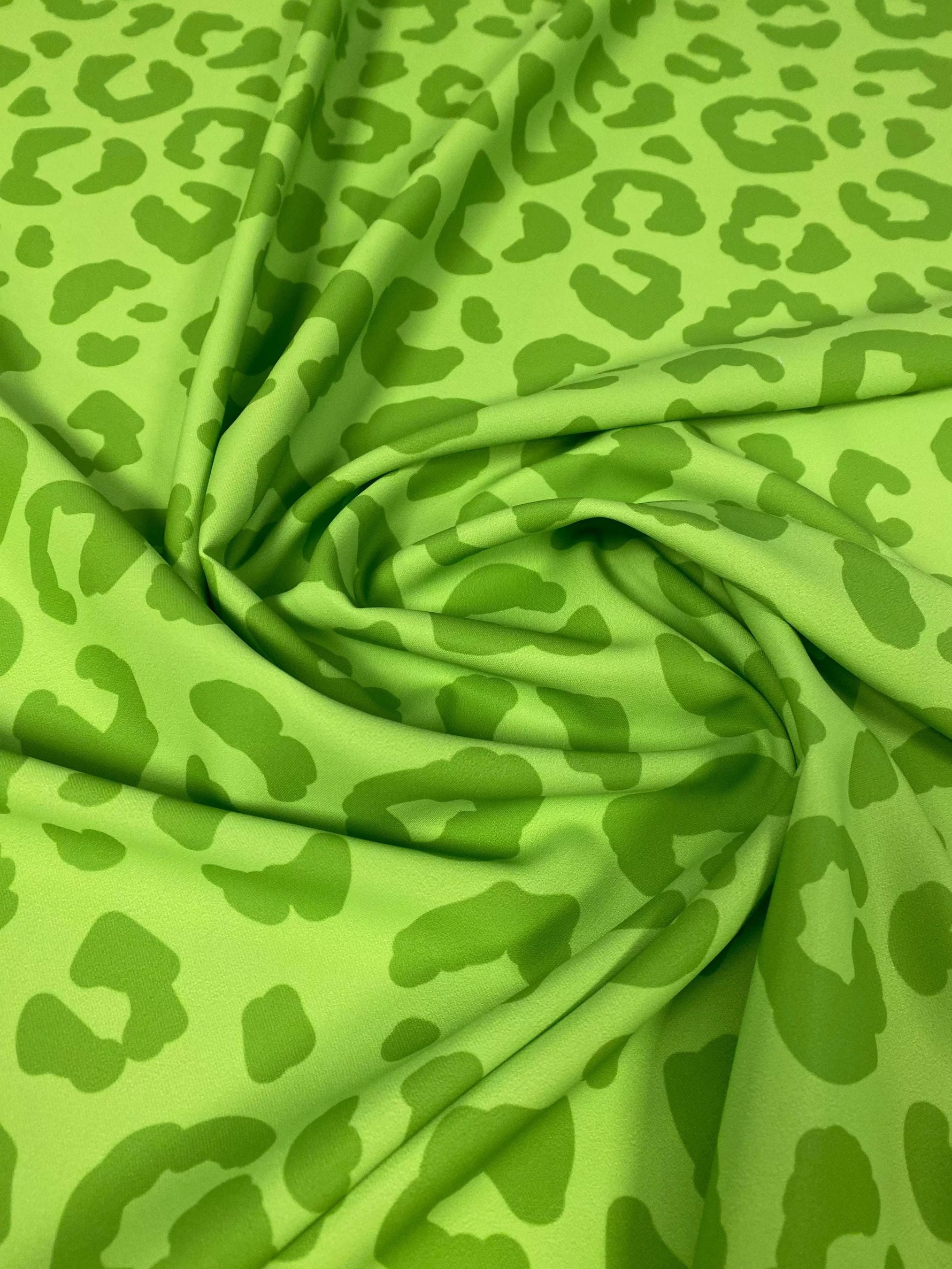 Close-up of neon green leopard print fabric with a 150cm width, folded to show texture and pattern details