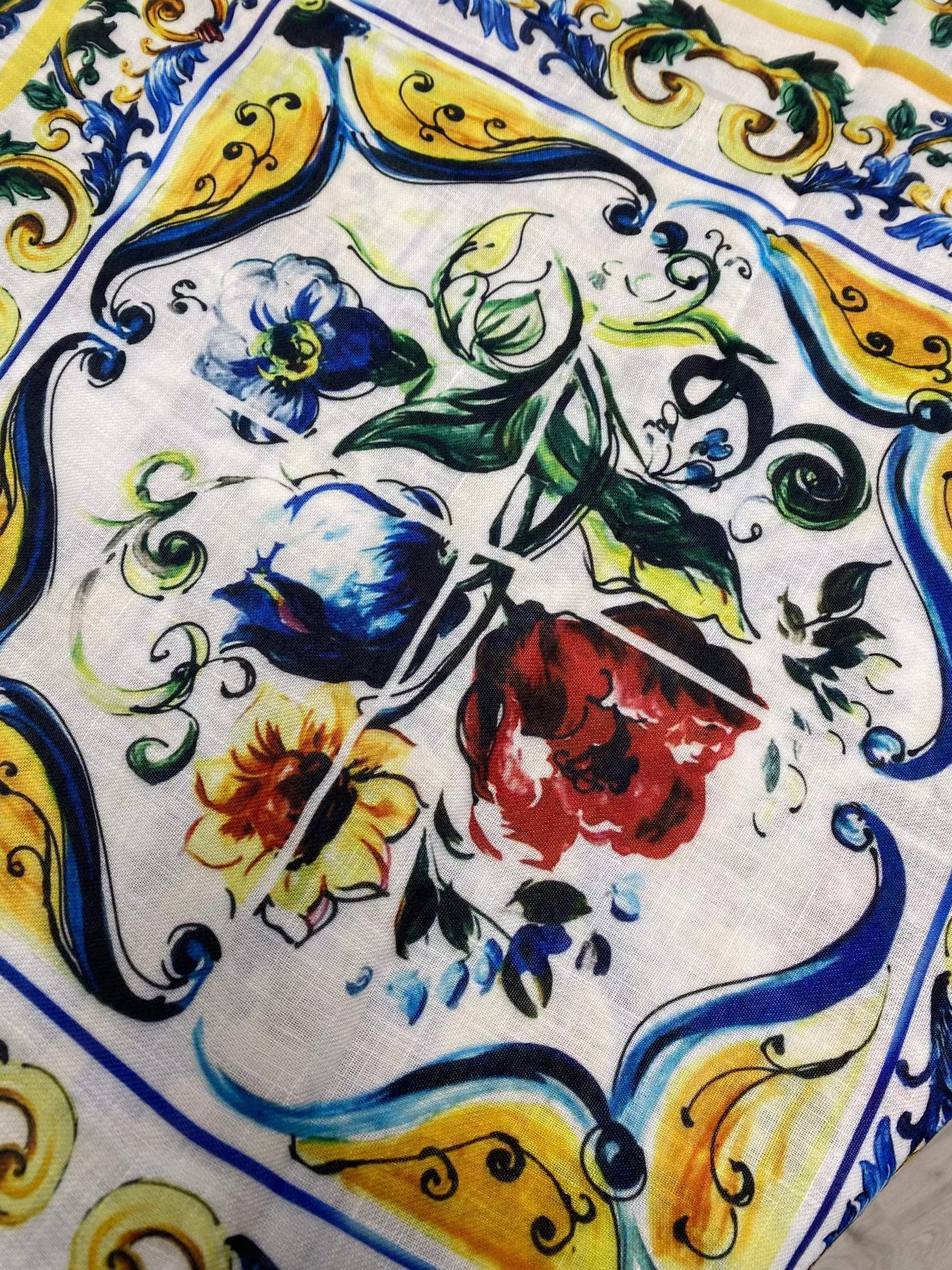 close-up of Big Mojalica Design Linen Fabric featuring vibrant floral and ornamental patterns in blue, yellow, red, and green on a white background