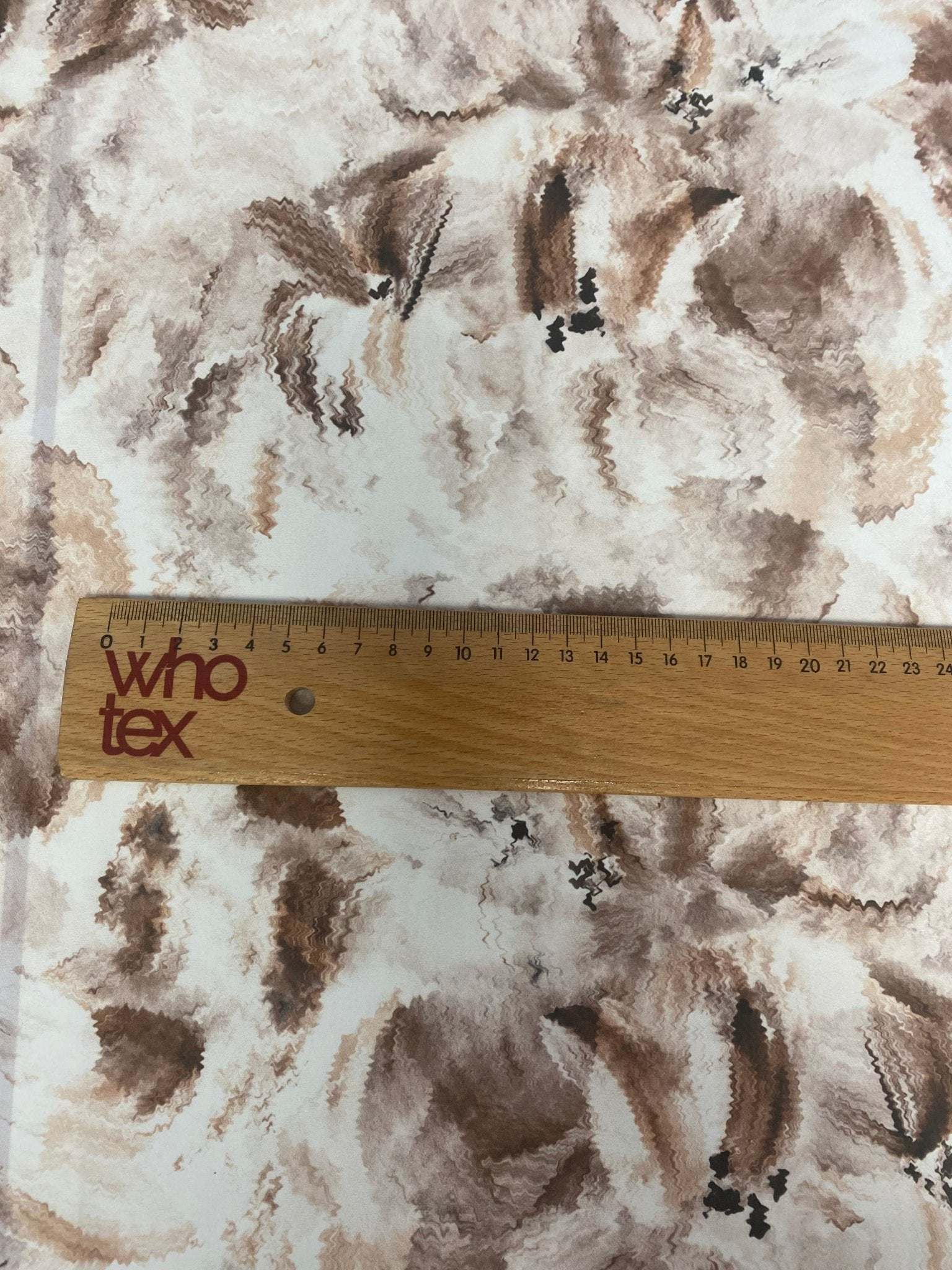 Abstract brown floral fabric with abstract flower patterns and ruler showing scale