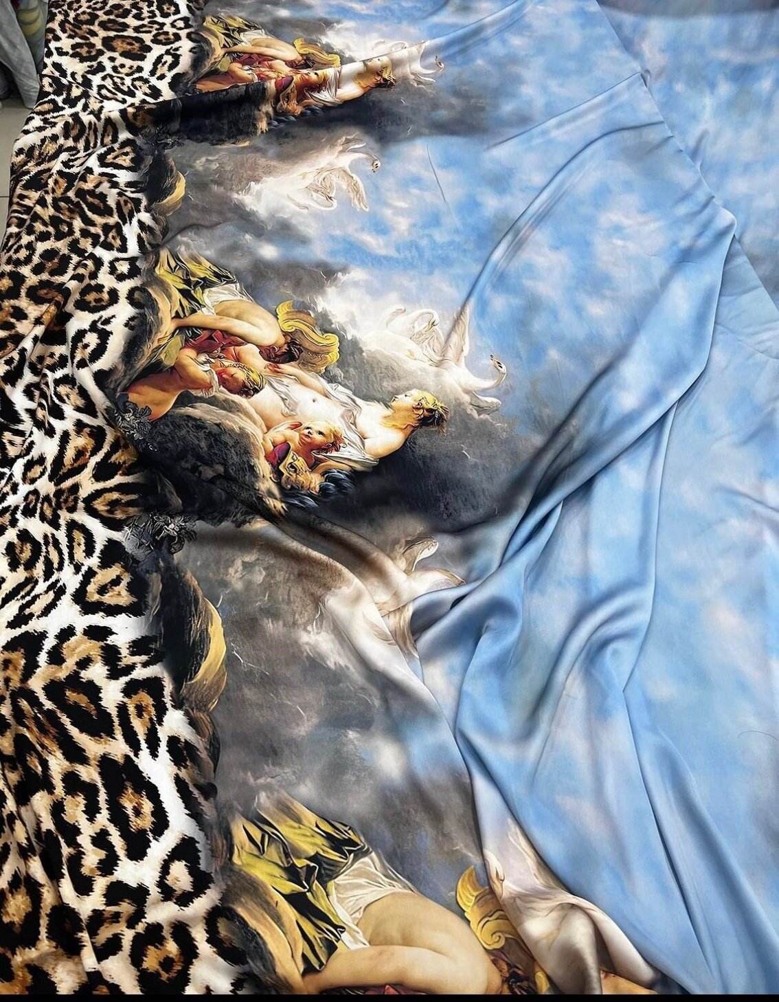 Angel Leopard Print Fabric featuring leopard and angel design with blue sky background, versatile for upholstery and crafts.