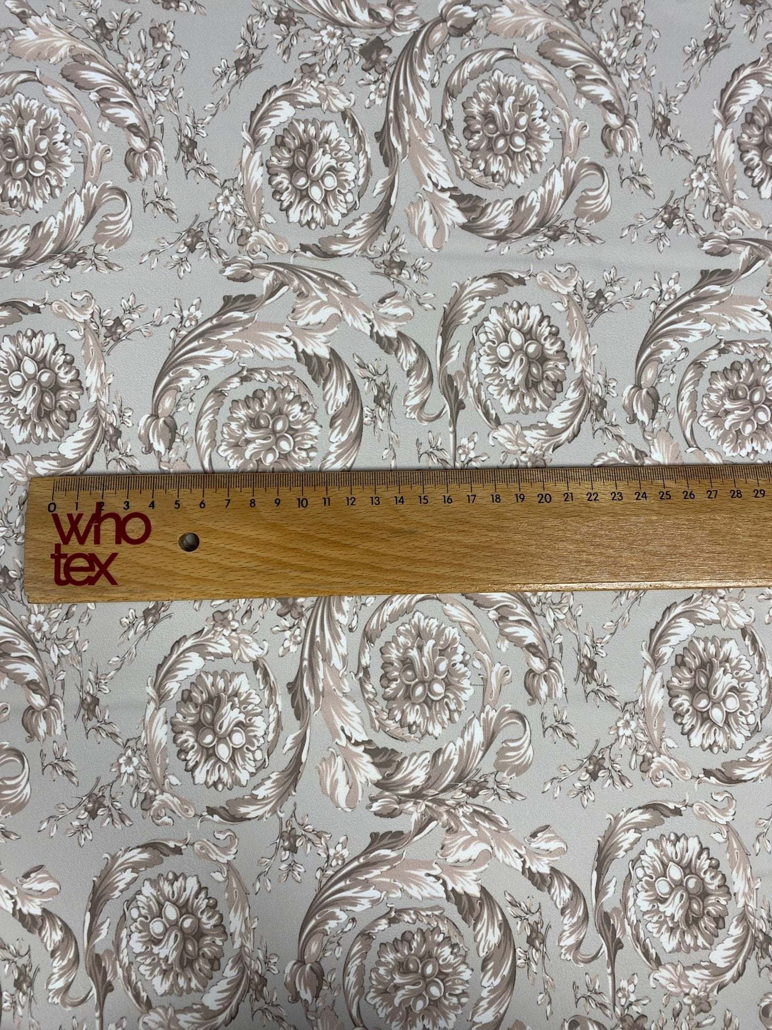 Baroque floral damask fabric in beige and taupe with classic ornate pattern and ruler for scale
