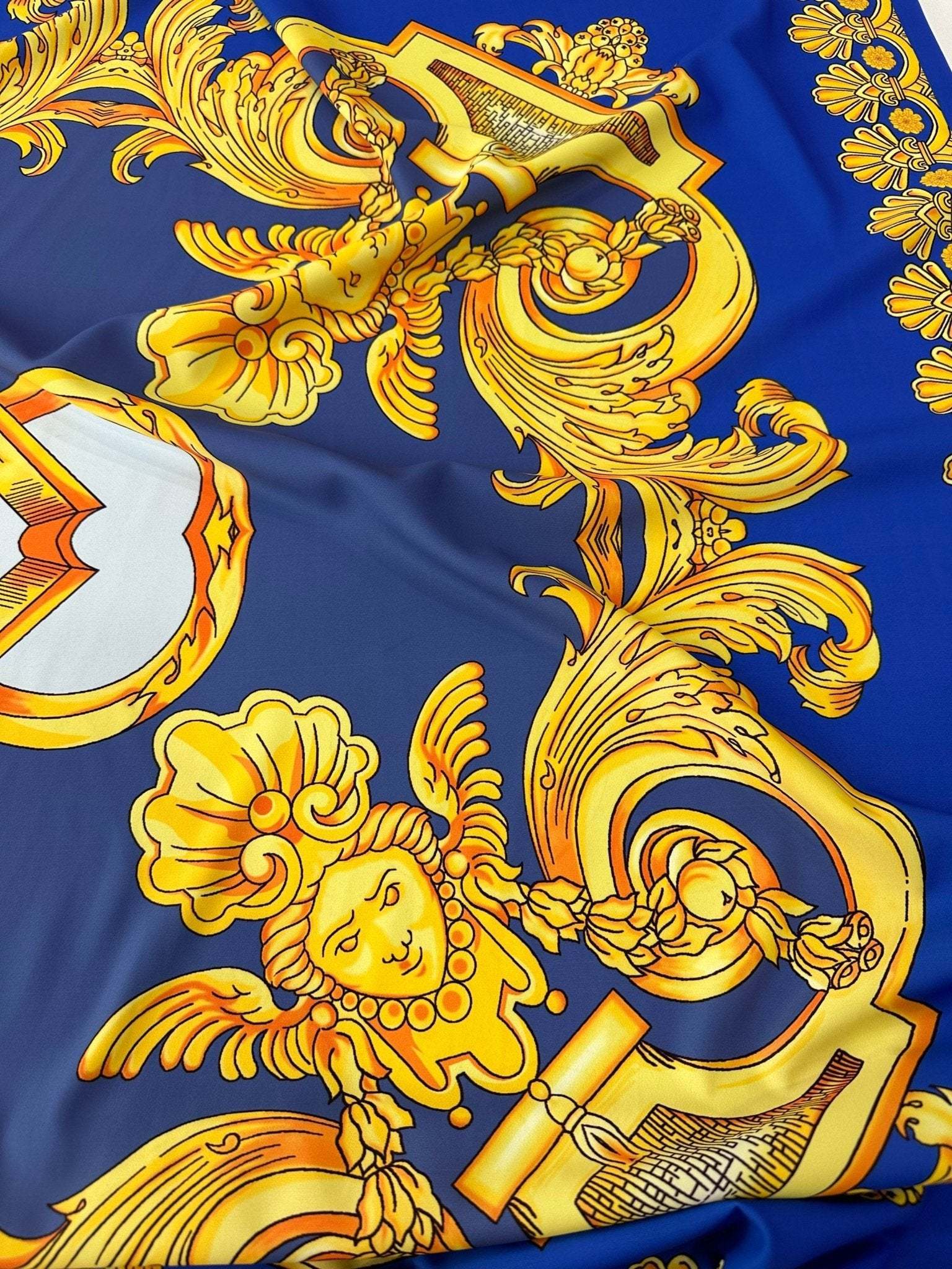 Baroque gold pattern fabric on royal blue background with intricate ornate designs and cherubic motifs