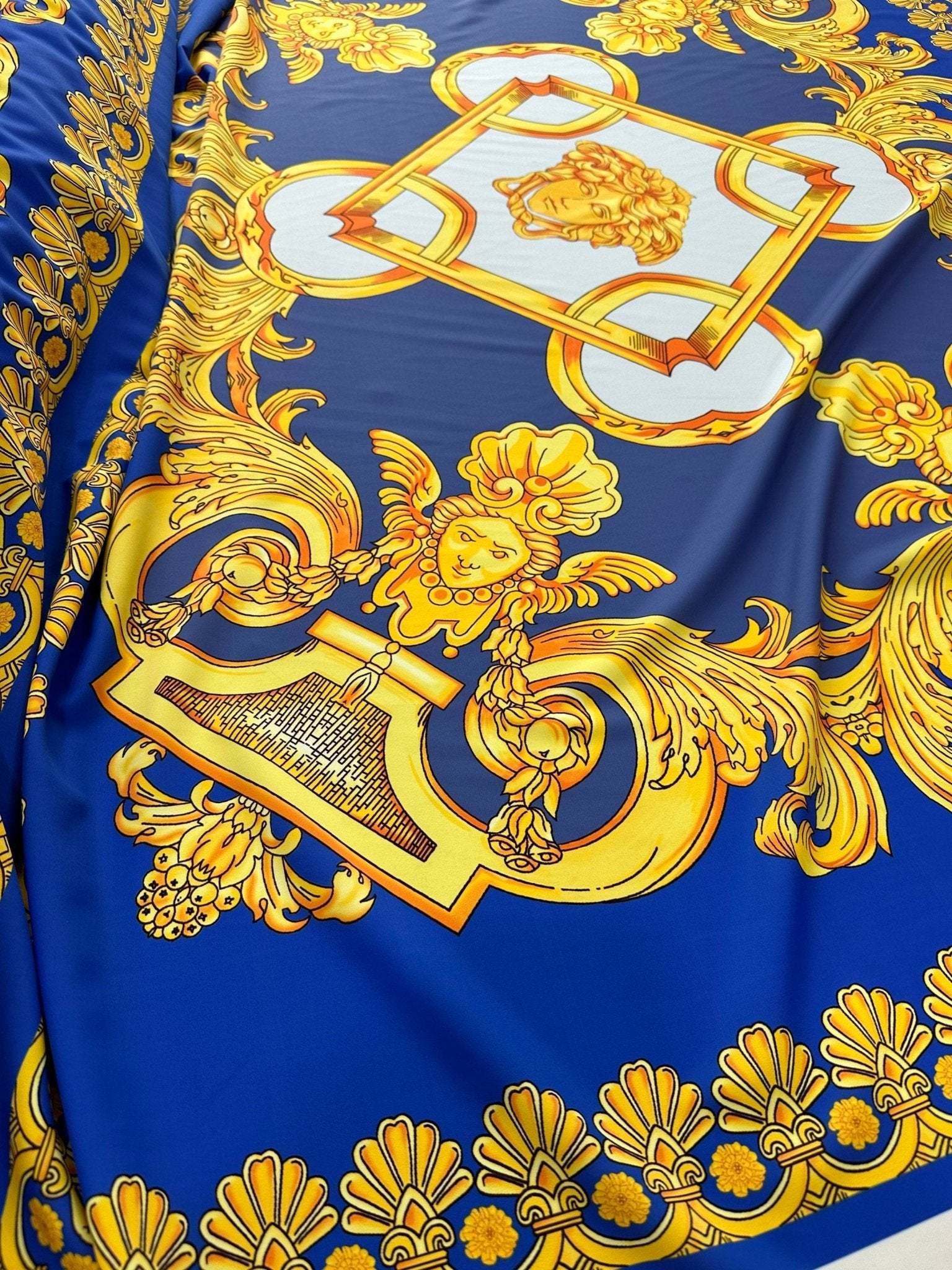 Baroque gold pattern fabric with intricate designs on royal blue background, ideal for upholstery and drapery.