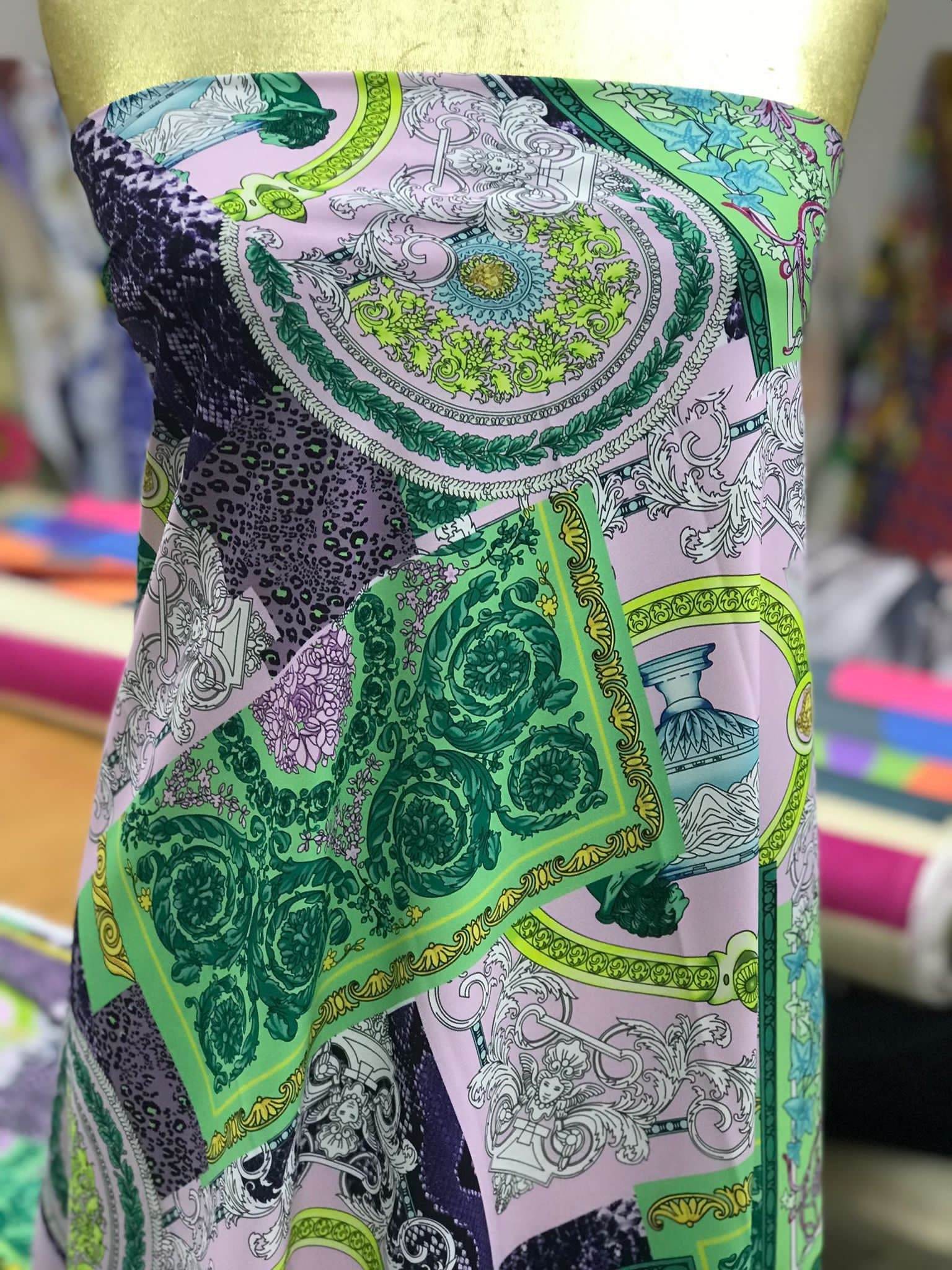 Baroque pattern fabric with green borders and soft pastel color palette displayed on a mannequin
