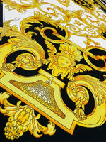 Baroque silky crepe fabric with intricate gold and black baroque pattern on white background
