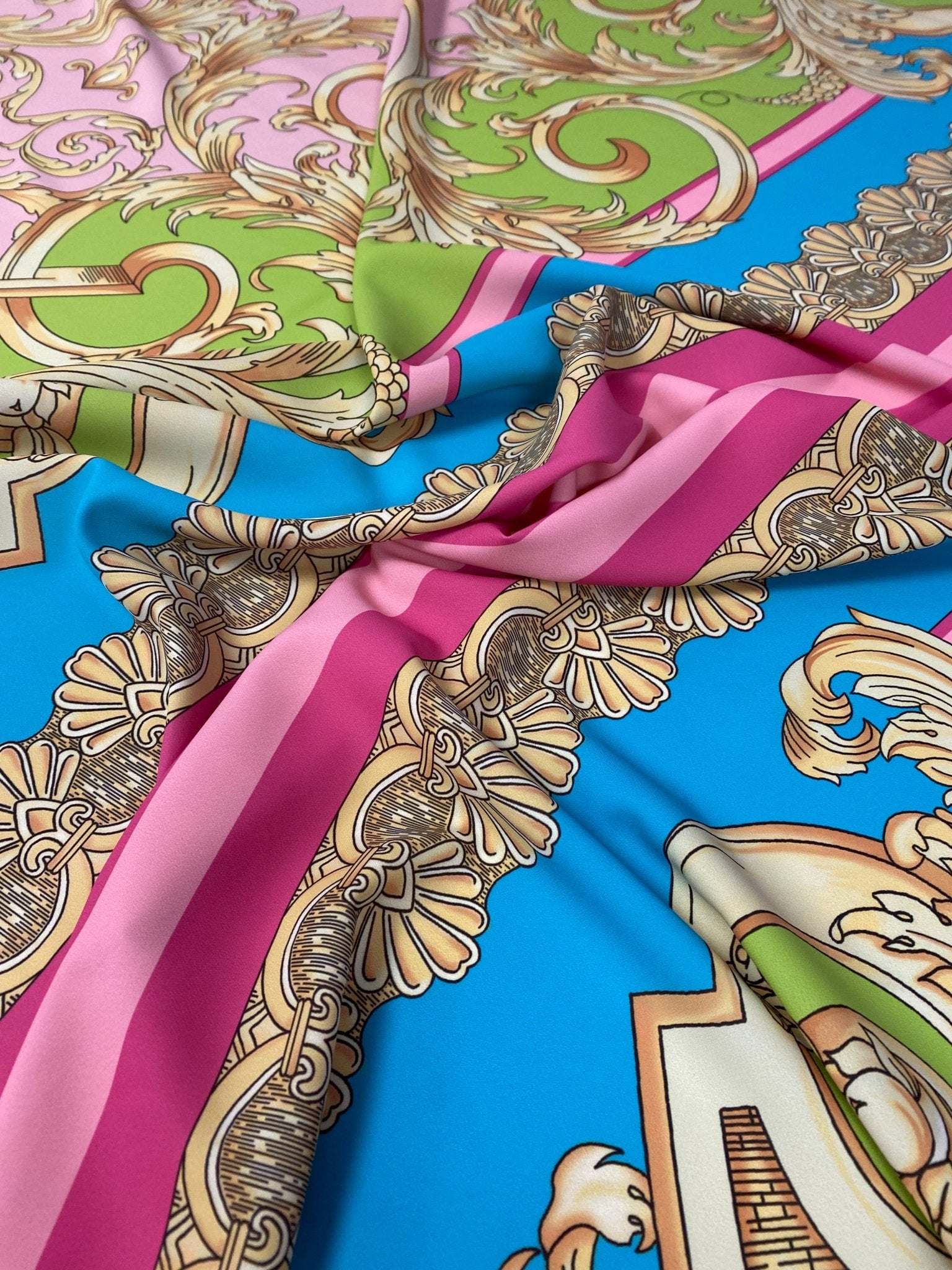 Baroque pink silky crepe fabric with ornate gold and green baroque patterns on blue background