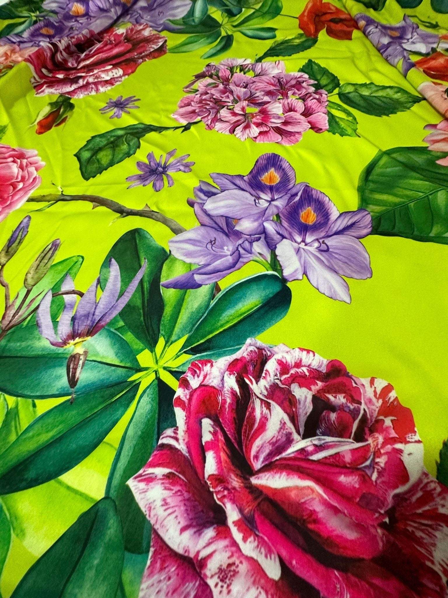 Floral neon green fabric with large pink, purple, and red rose pattern and green leaves.
