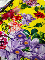 Bright yellow fabric with large floral pattern featuring purple, red, and pink flowers and green leaves