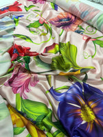 Close-up of vibrant tropical floral fabric with colorful flowers and green leaves on a light background