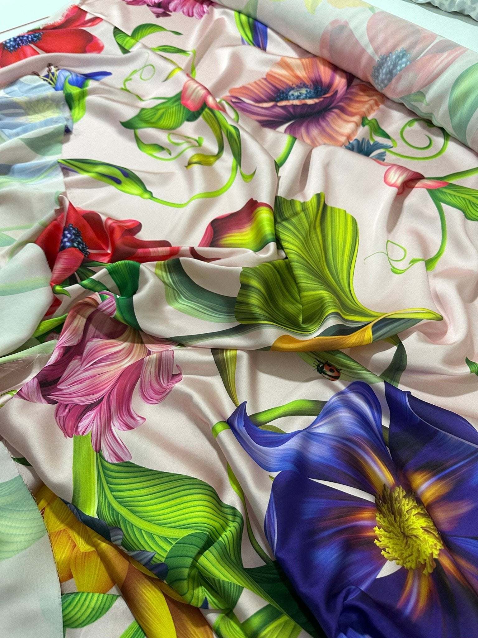 Close-up of vibrant tropical floral fabric with colorful flowers and green leaves on a light background