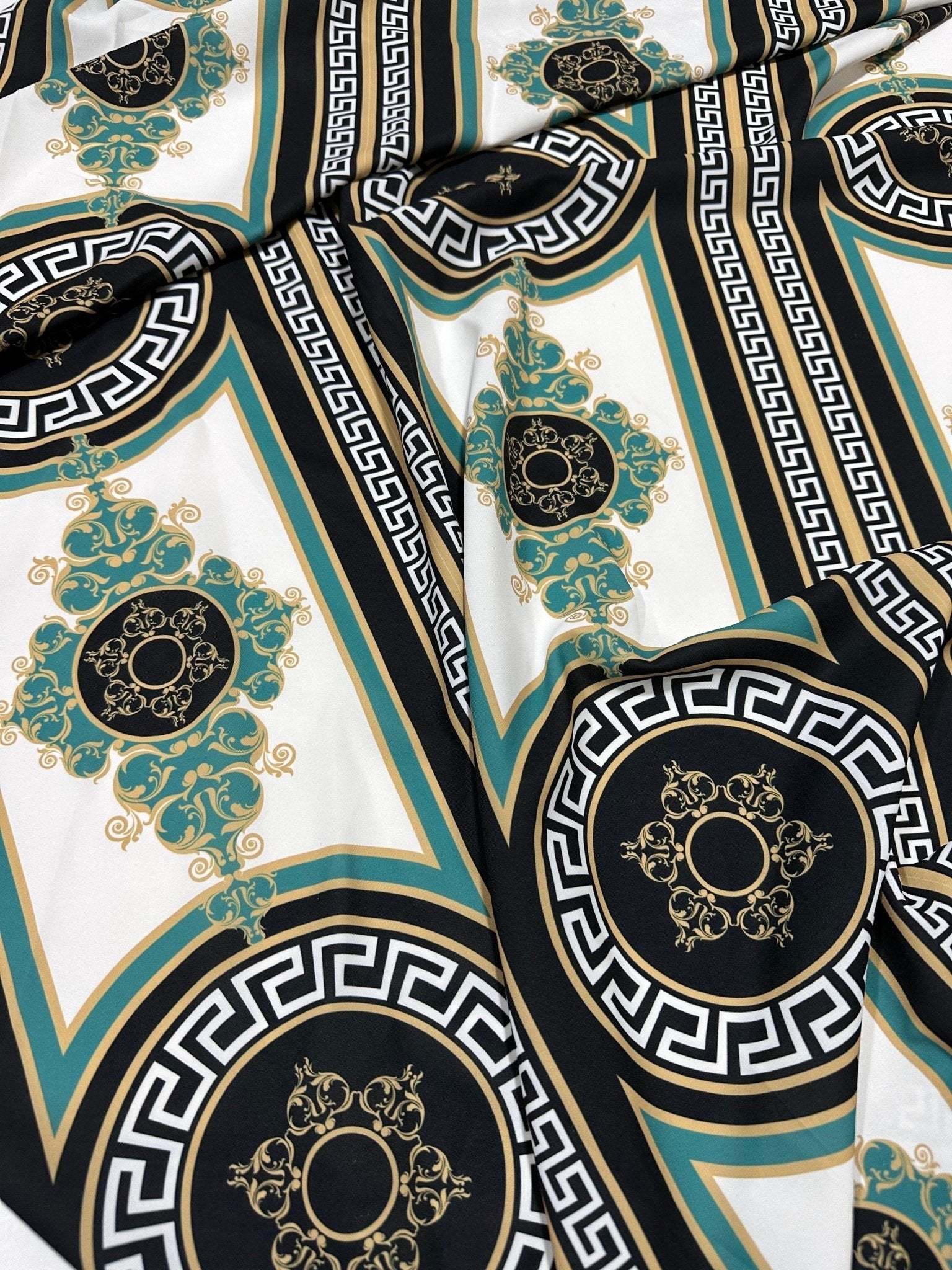 Greek key pattern fabric with black, white, green, and gold decorative design for upholstery and drapery.