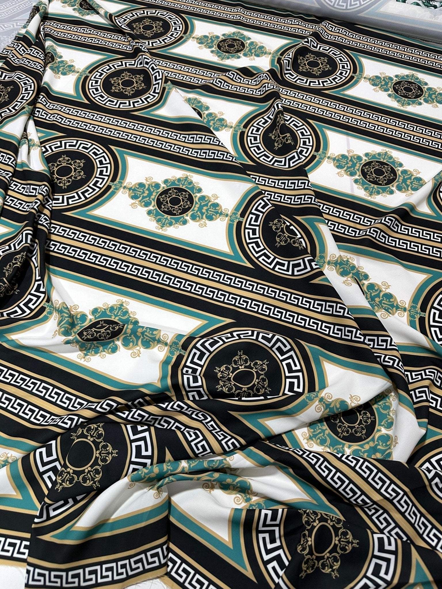 Greek Key Pattern Fabric with black, gold, and teal ornate circular and linear designs on white background