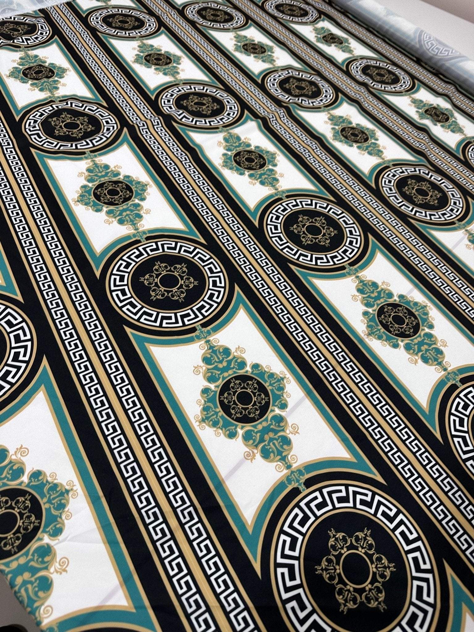 Greek Key Pattern Fabric with black, white, and gold intricate geometric and floral designs on a wide fabric roll