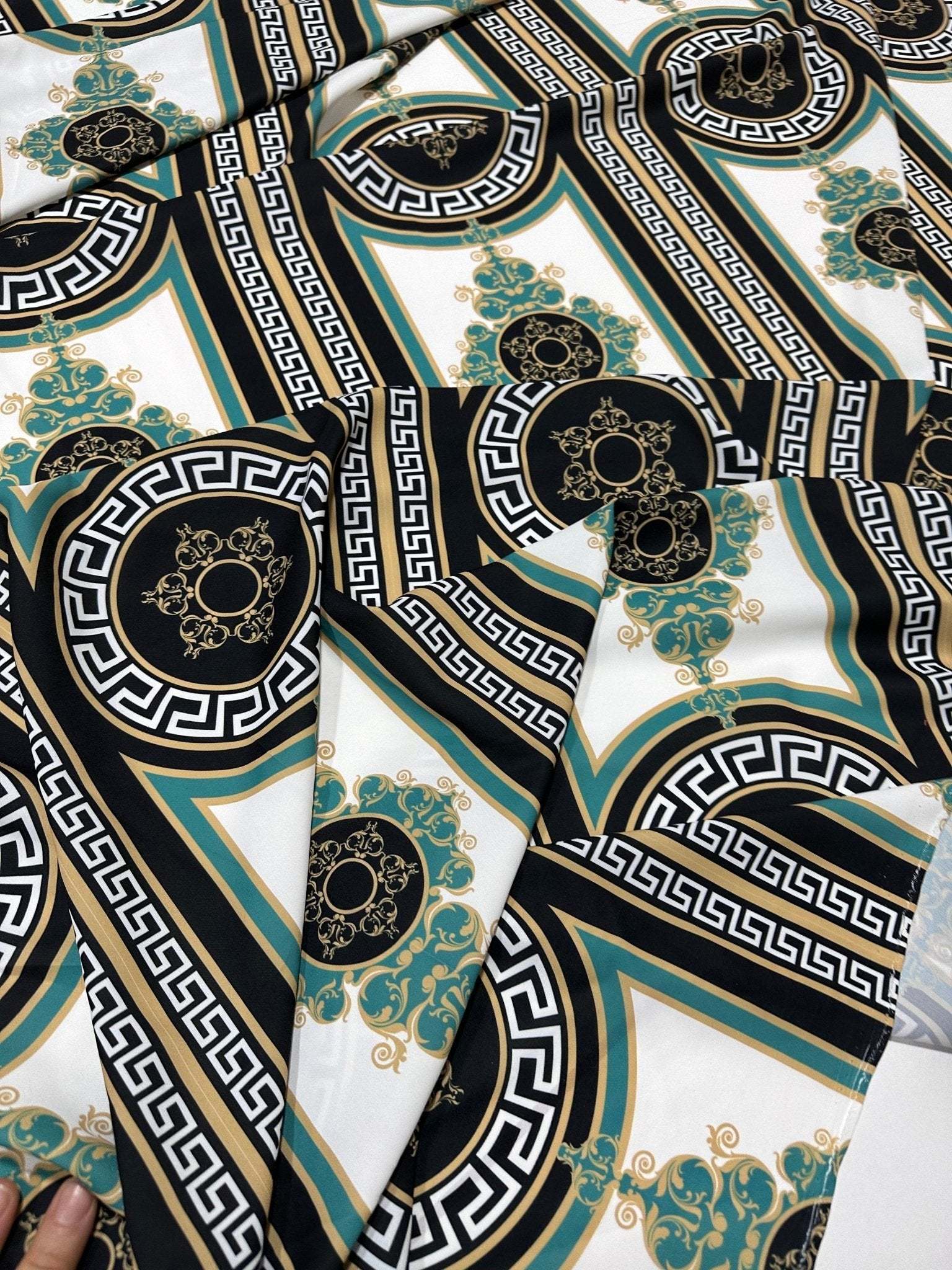 Close-up of Greek Key Pattern Fabric with black, white, gold, and teal geometric and ornamental designs