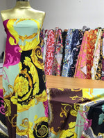 Black pink fabric with Greek key and baroque print on dress form and fabric rolls in background