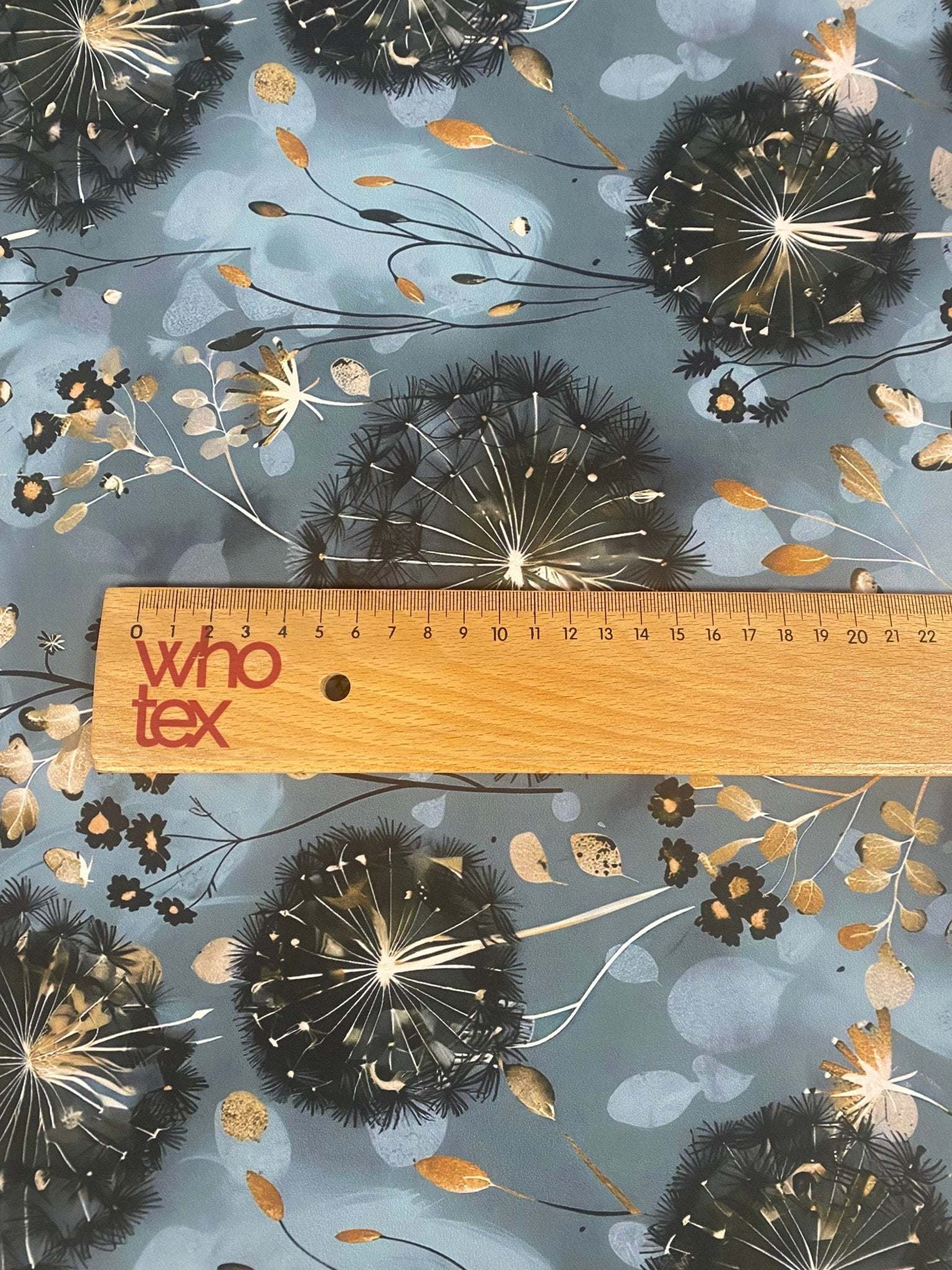 Blue grey fabric with dandelion print and floral accents, soft and durable textile for sewing projects