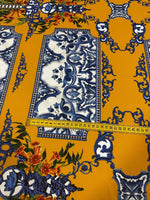 Elegant mustard yellow Baroque floral fabric with intricate blue and white patterns and colorful floral accents, featuring a measuring tape showing fabric width.