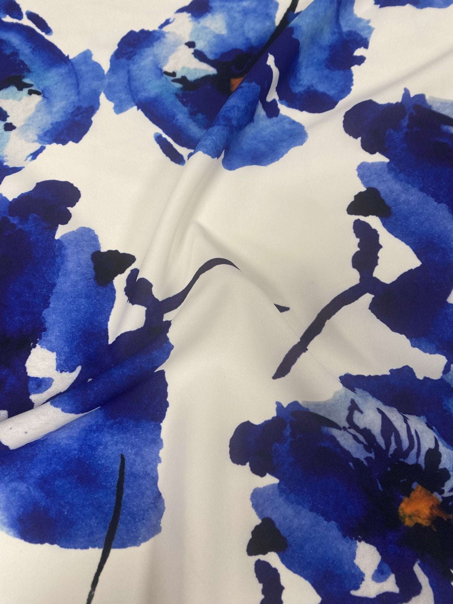 Bold blue watercolor floral fabric with vibrant flower patterns on a soft white background