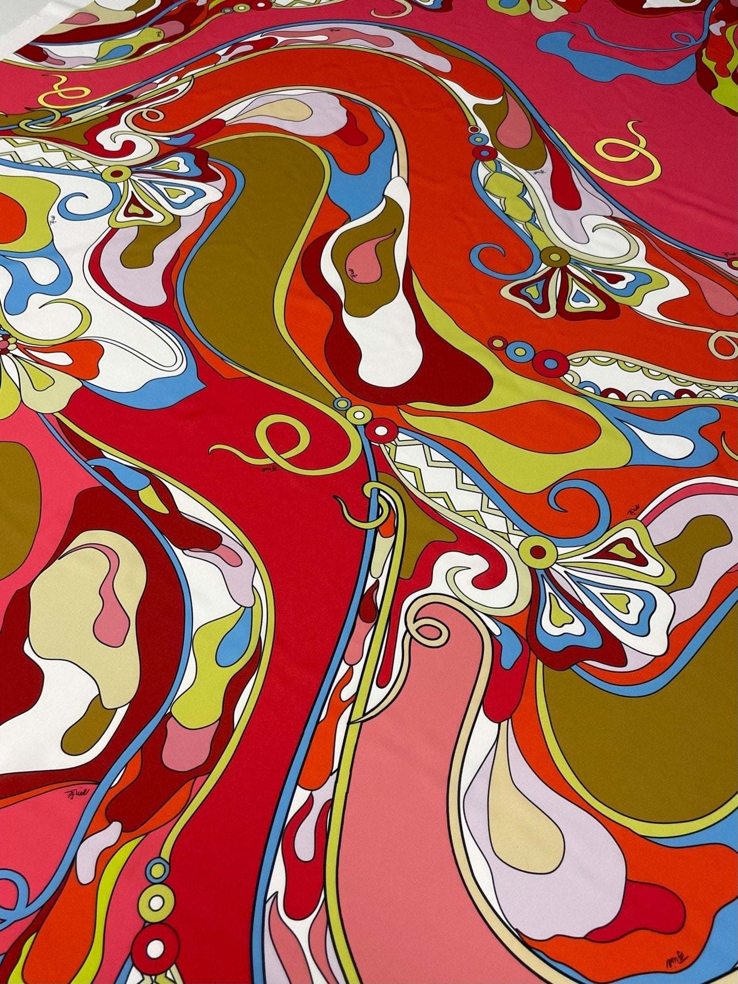 Colorful abstract swirl pattern fabric with vibrant red, pink, orange, blue, and olive green hues, ideal for crafting and sewing projects