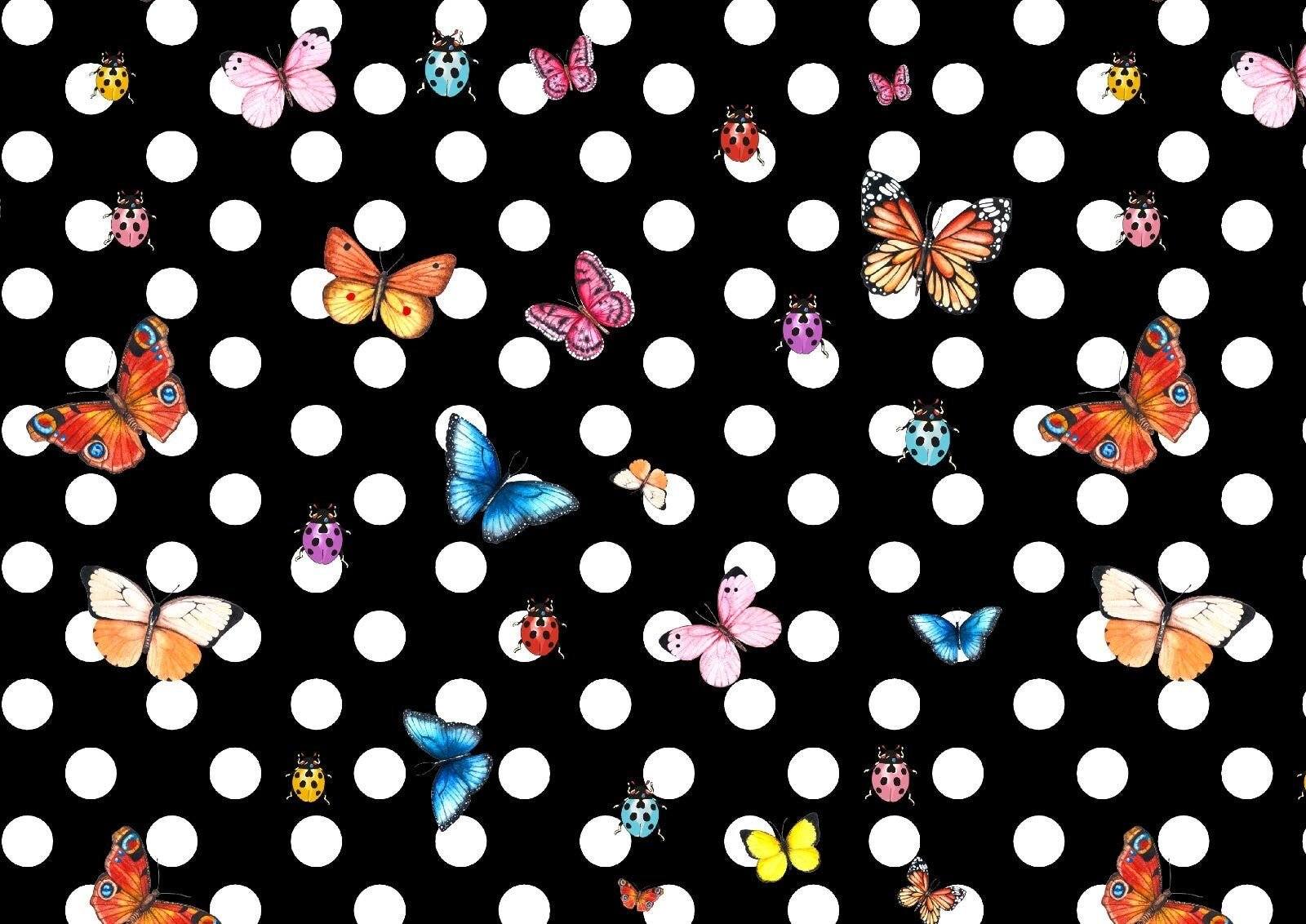 Black fabric with white polka dots featuring colorful butterfly and ladybug patterns for sewing projects.