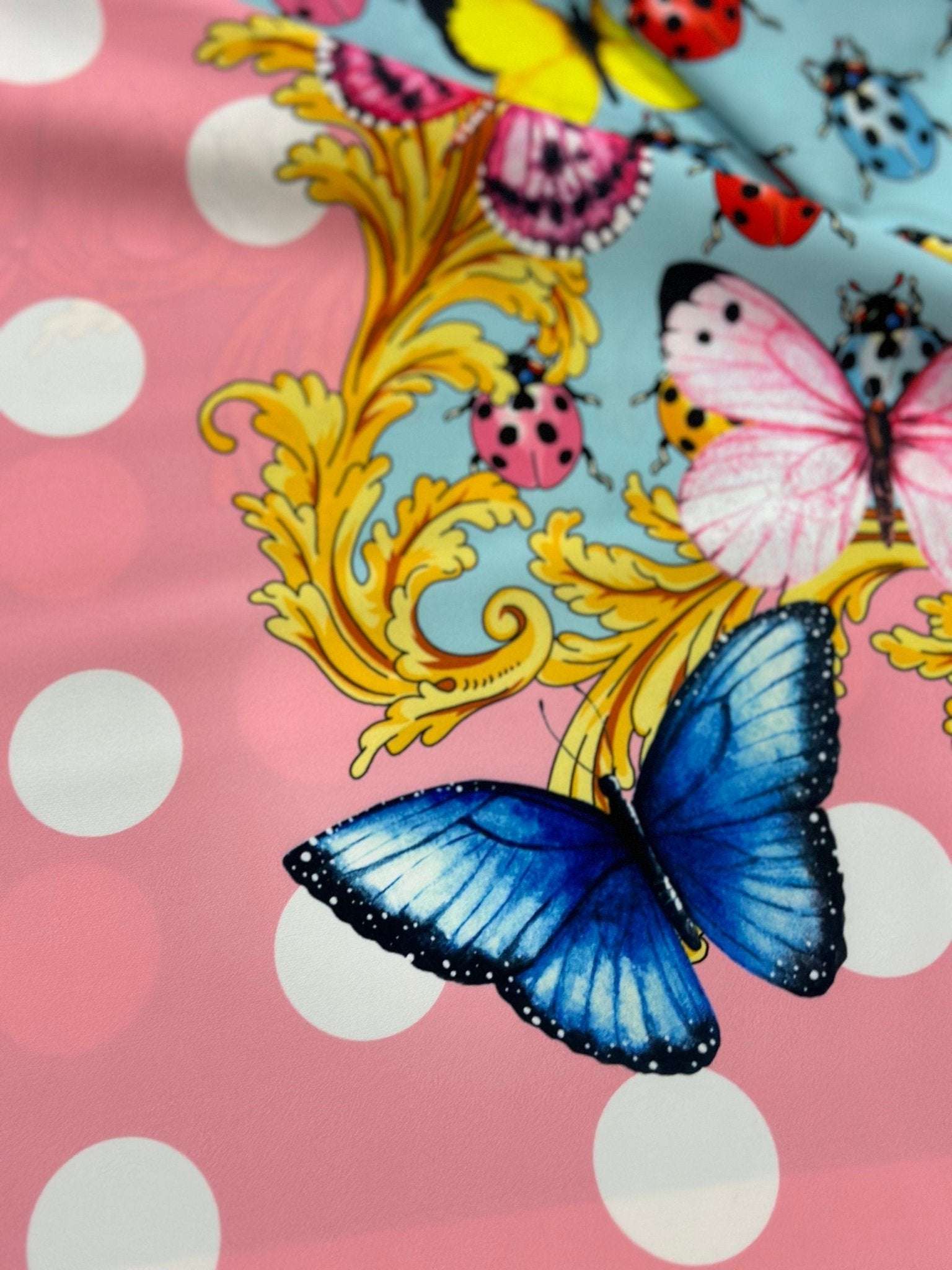 Colorful butterfly and ladybug pattern fabric with polka dot border on pink background