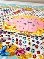 Colorful butterfly and polka dot print fabric with vibrant insects and decorative golden patterns on a white and pastel background