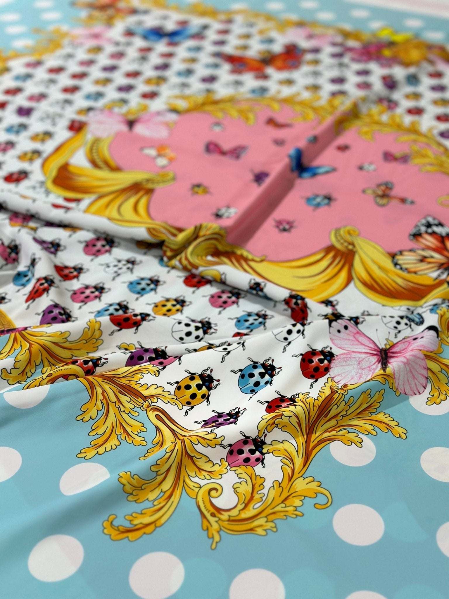 Colorful butterfly and polka dot print fabric with gold ornate detailing on blue background