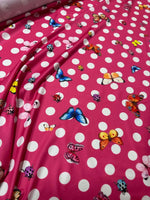 Bright pink butterfly polka dot fabric with colorful butterflies and white polka dots for crafting and sewing projects