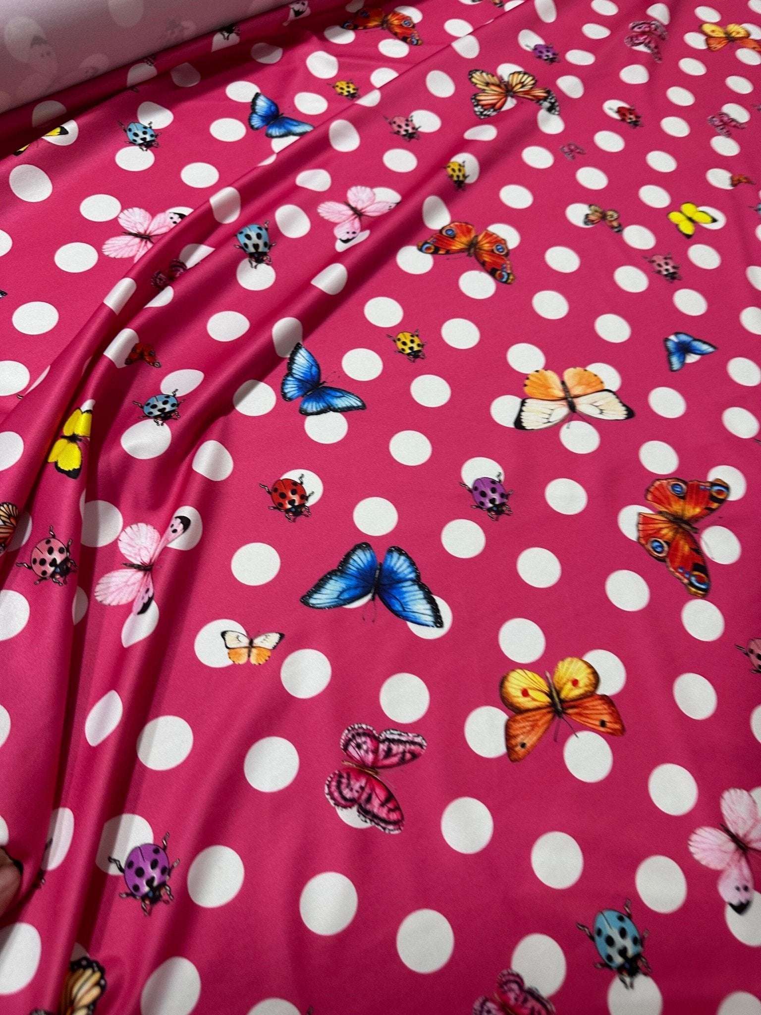 Bright pink butterfly polka dot fabric with colorful butterflies and white polka dots for crafting and sewing projects