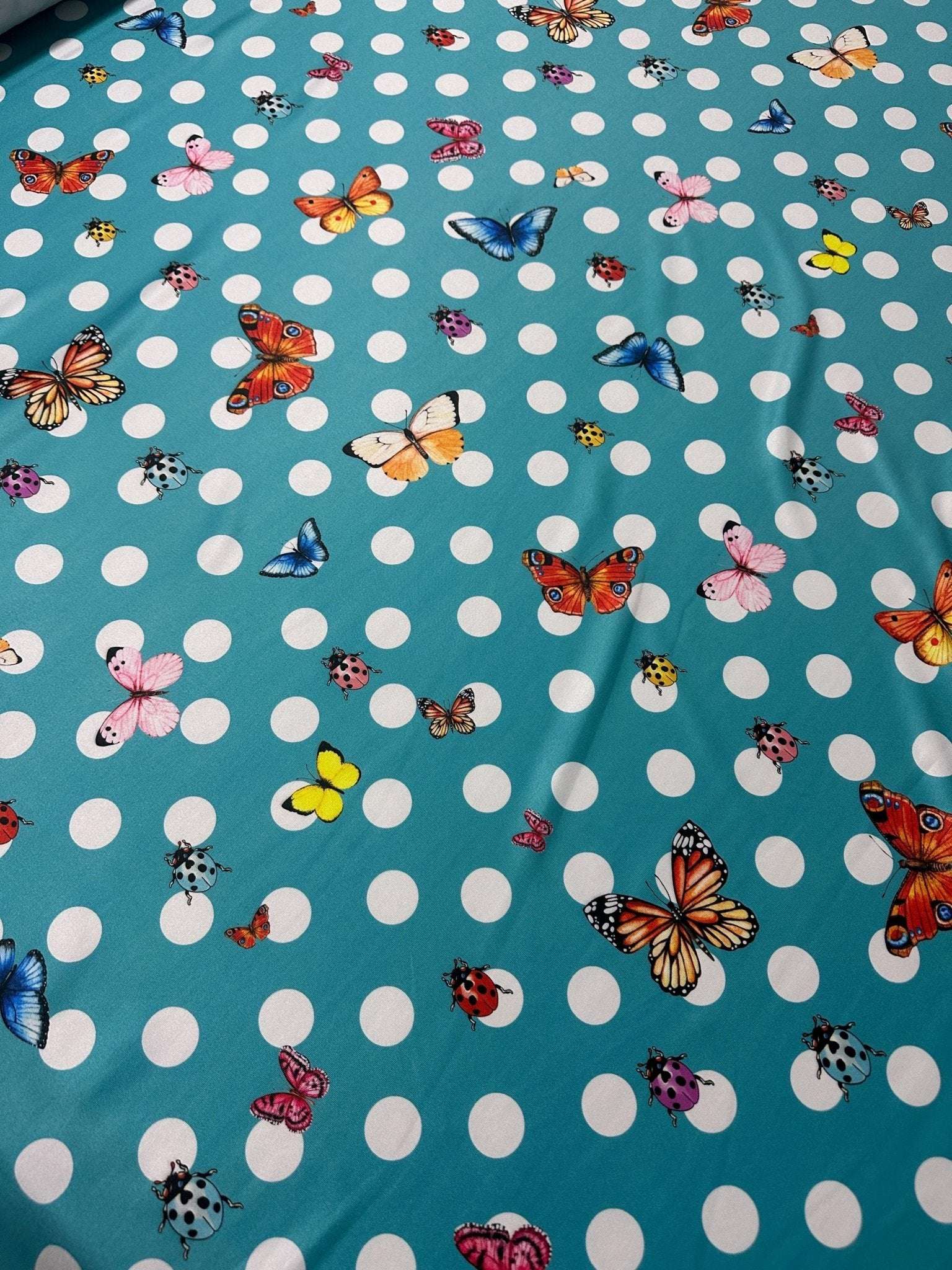 Baby blue fabric with white polka dots and colorful butterfly prints