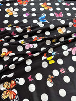 Black fabric with white polka dots and colorful butterfly prints for sewing and crafts