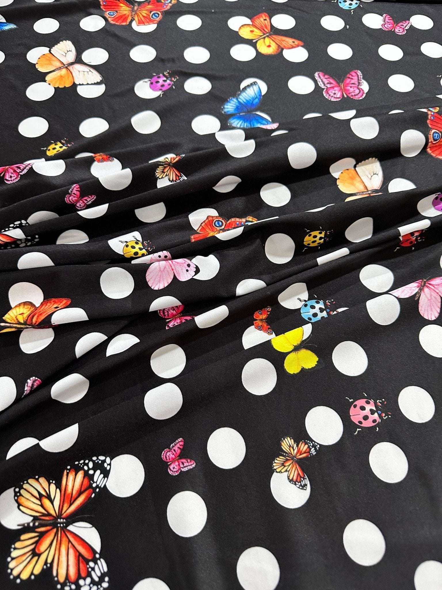 Black fabric with white polka dots and colorful butterfly prints for sewing and crafts