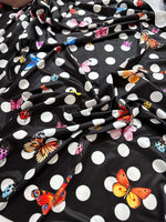 Black fabric with white polka dots and colorful butterfly designs for sewing and crafts